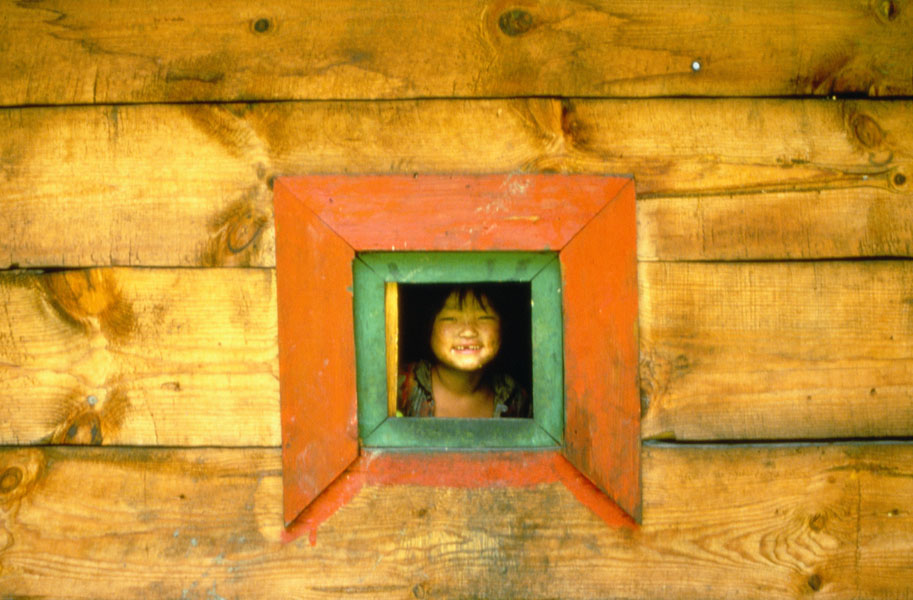 西藏东南．一名察隅族孩童透过木头房子的窗户观看景物
