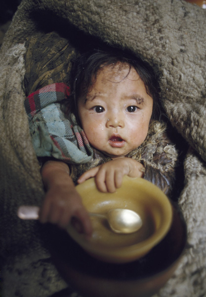 西藏羌塘草原上帐篷，手持小碗和汤匙的小女孩
