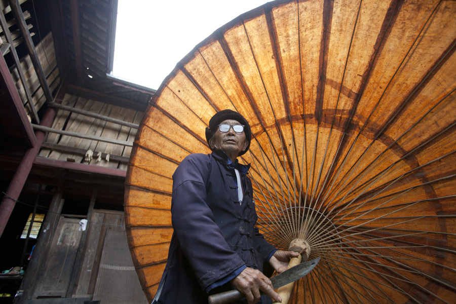 荥阳村的郑老先生展示手工製作的大油纸伞。云南腾冲和顺乡。